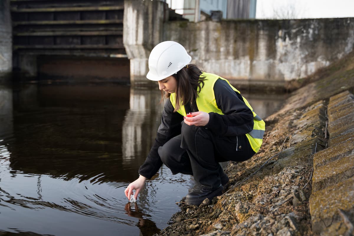 Ingeniera ambiental tomando una muestra de agua en campo